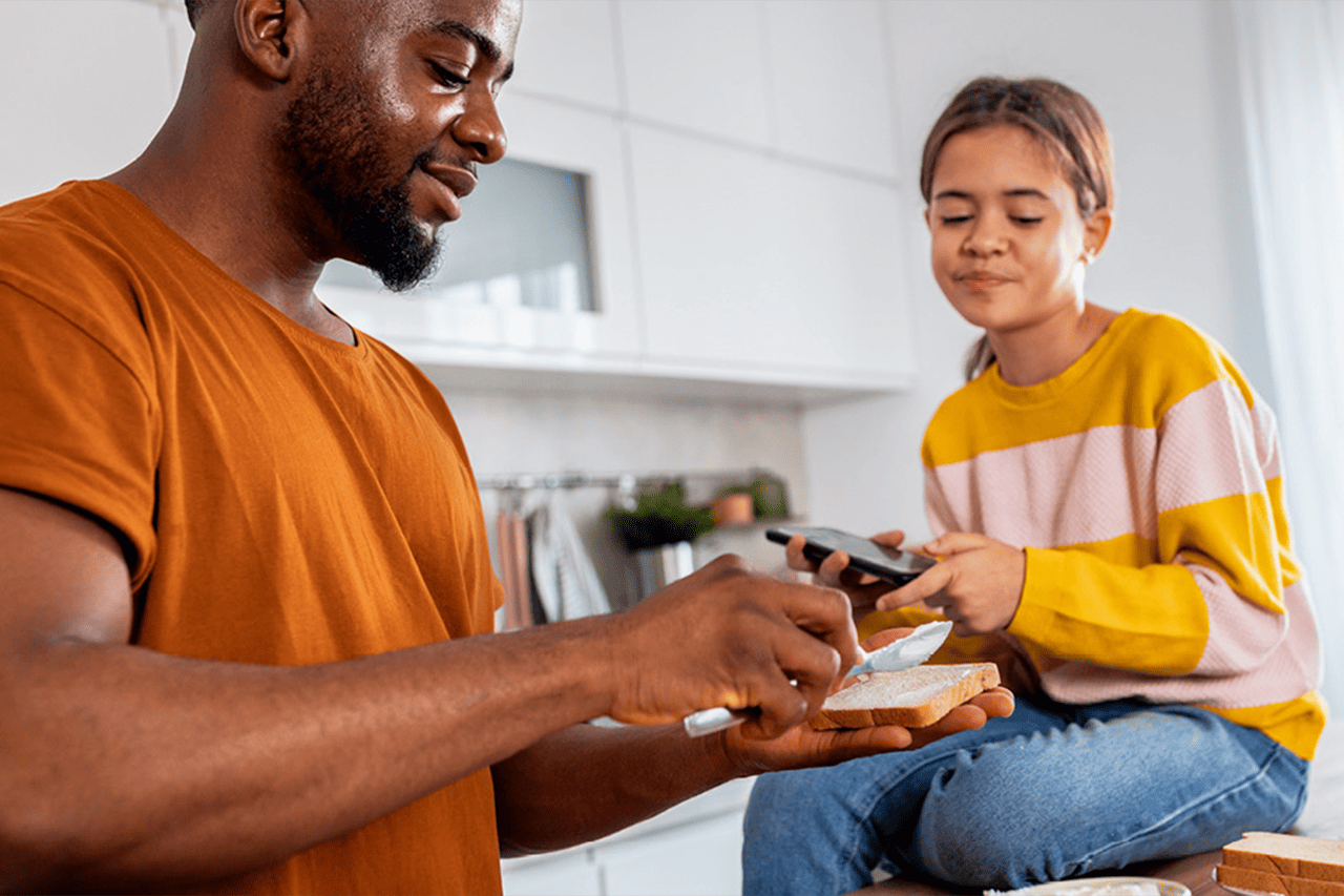 Père et fille tartinent le pain.